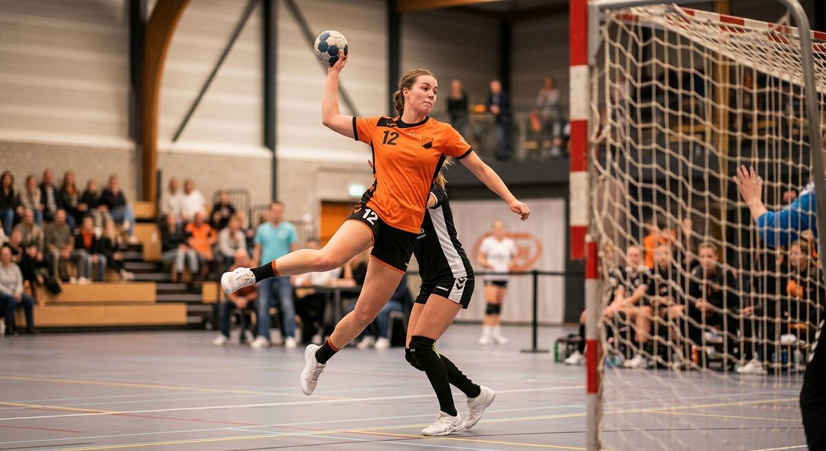Handbalspeelster schiet in de sporthal op het doel tijdens een wedstrijd